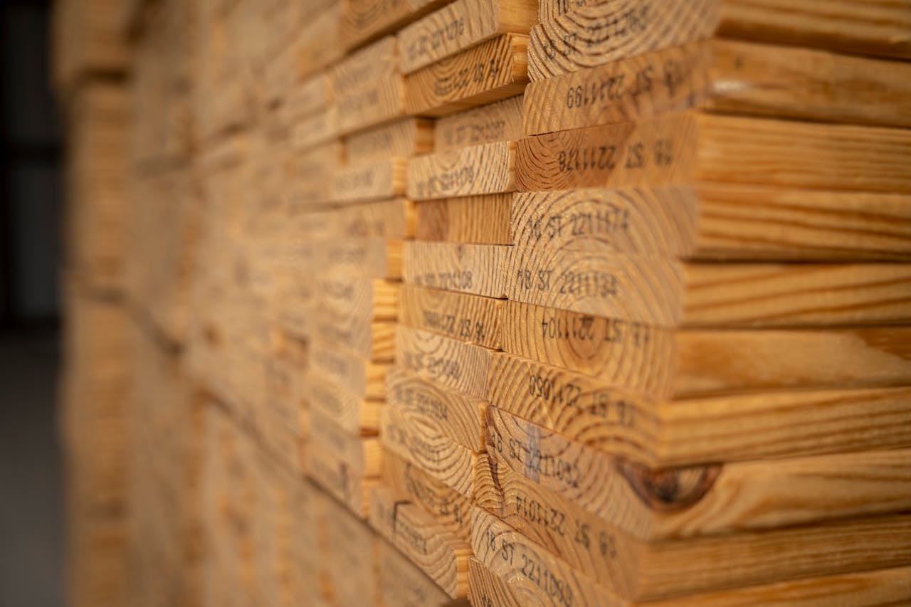 journey-02 Detailed view of neatly stacked timber planks displaying texture and grain in a warehouse setting.